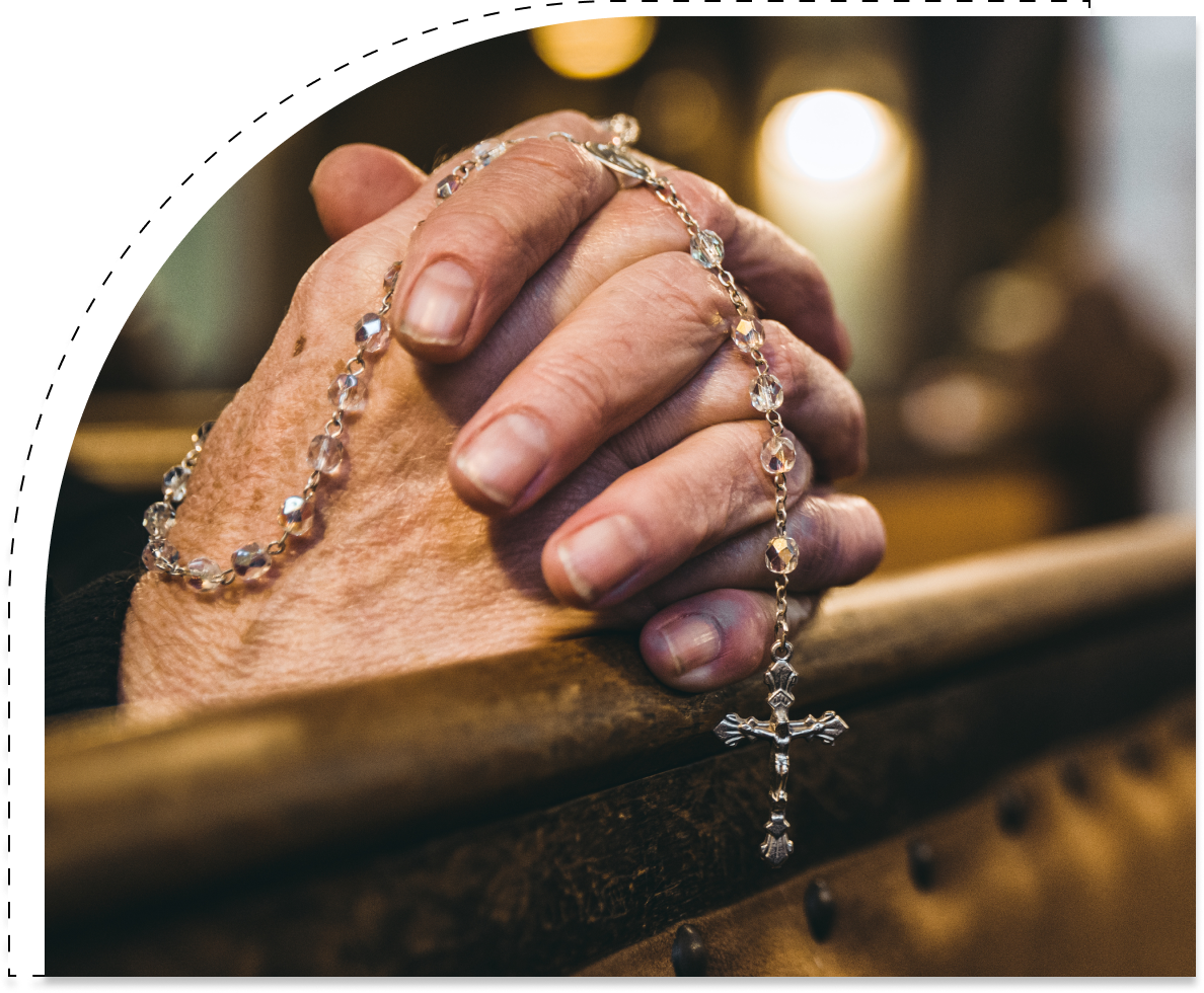 A person with their hands clasped together holding a rosary.