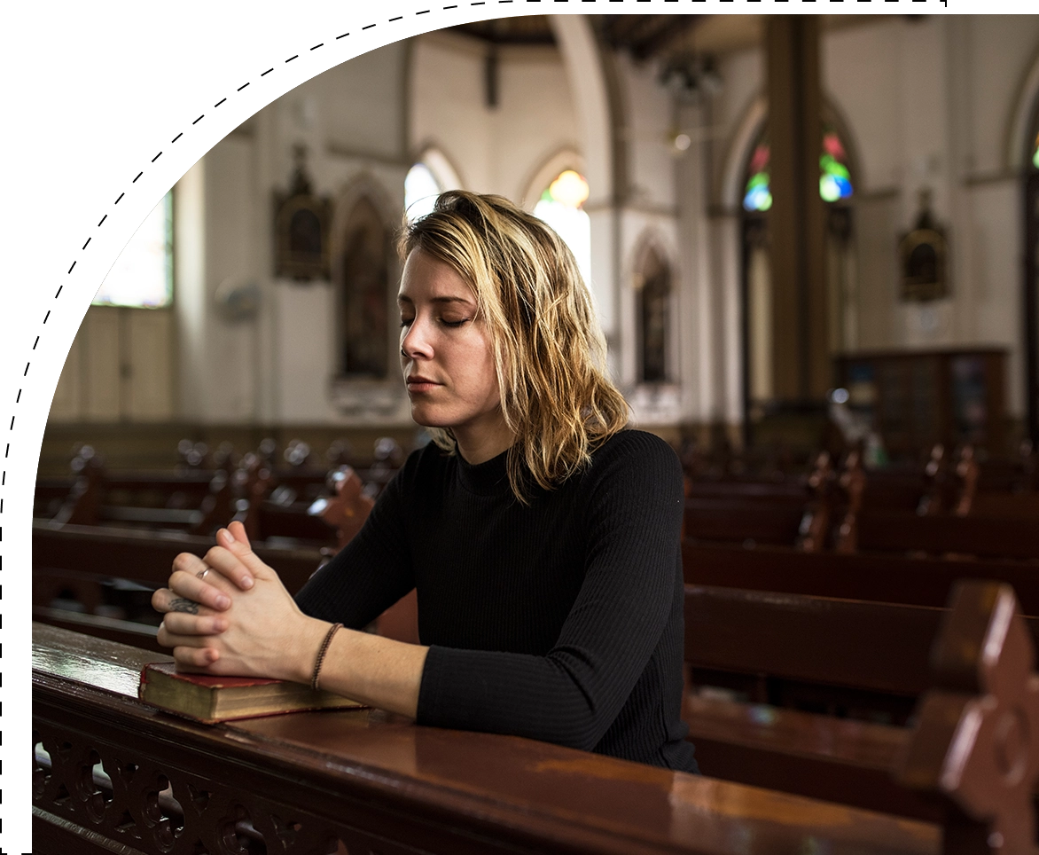 A woman sitting in the middle of a church pew.