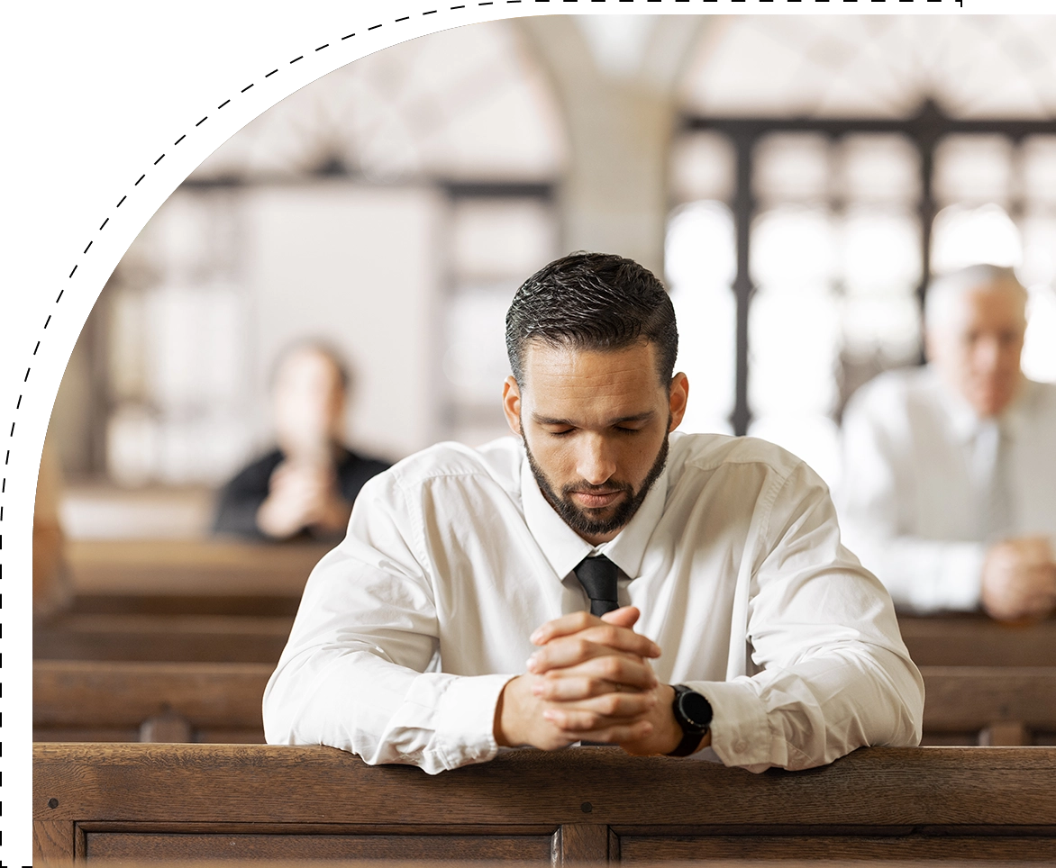 A man sitting in the middle of a pew with his hands clasped together.