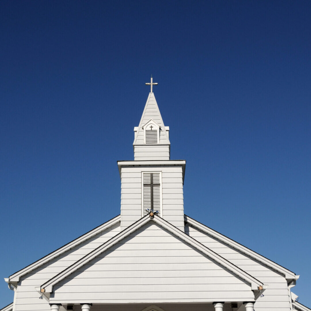 A white church with a cross on top of it.