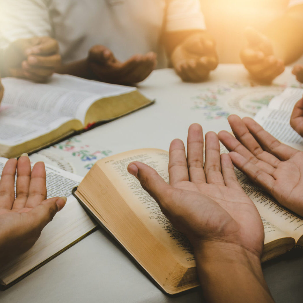 A group of people sitting around a table with open hands.