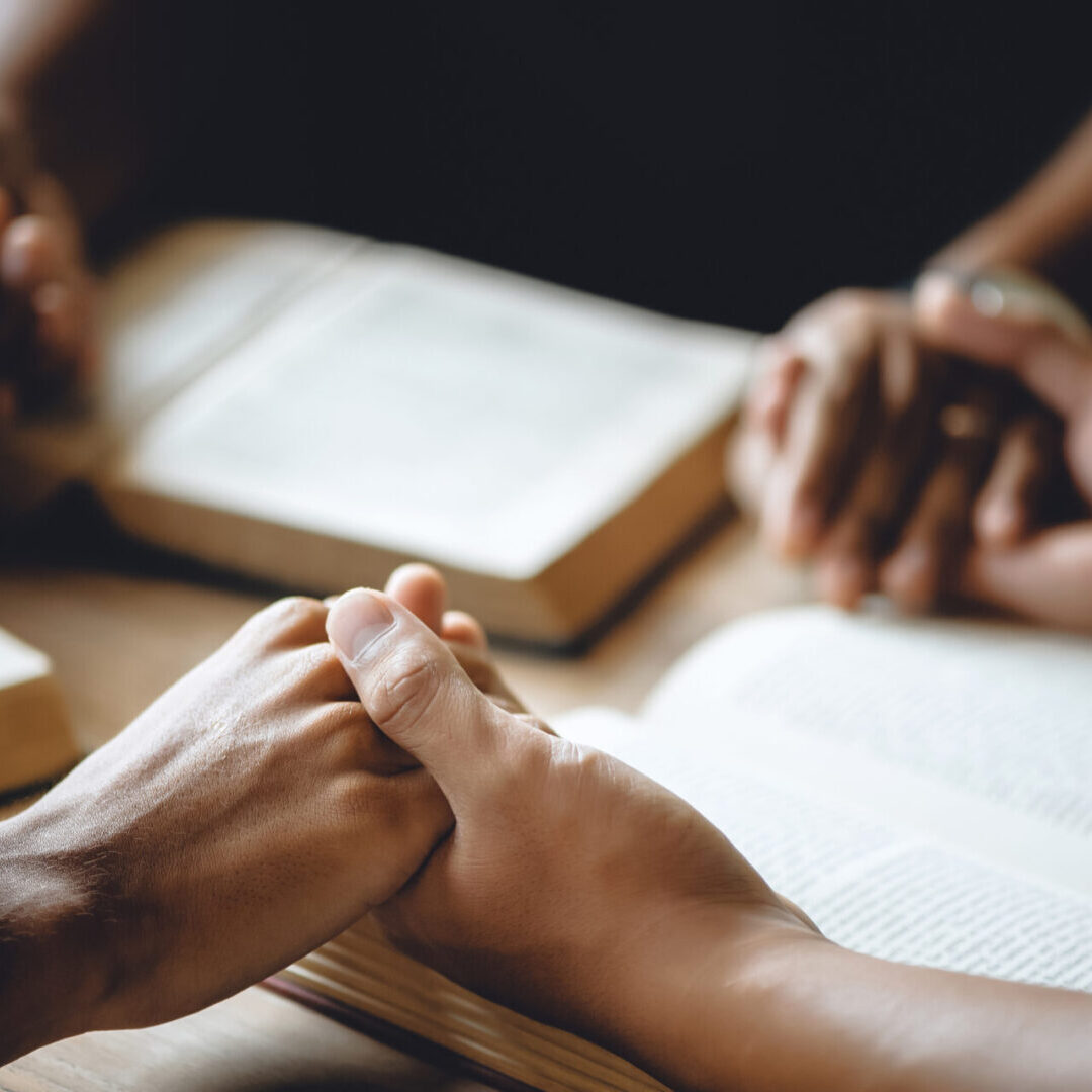 A group of people holding hands at a table.