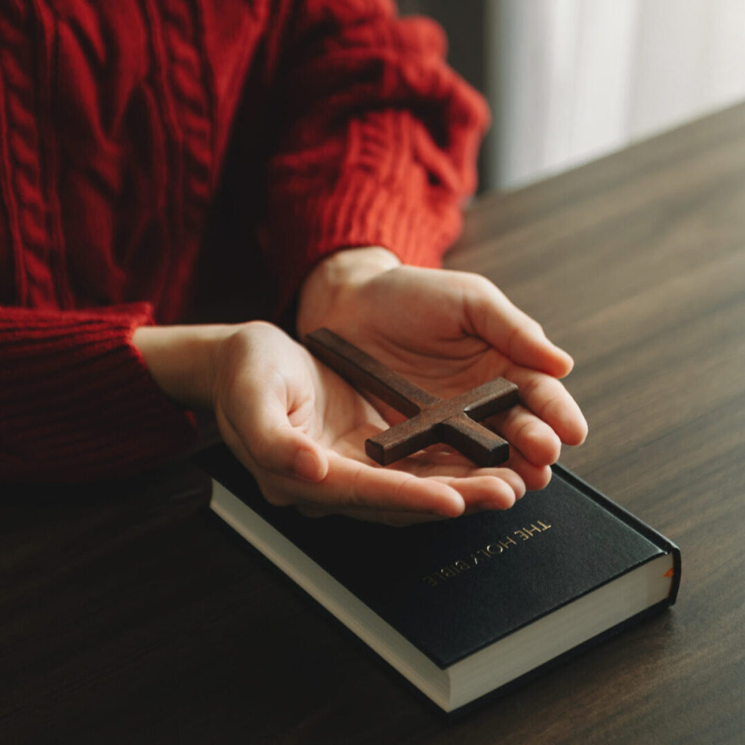 A person holding a cross on top of a book.