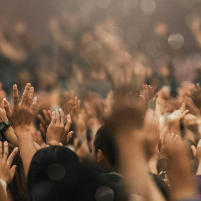 A crowd of people with their hands up in the air.