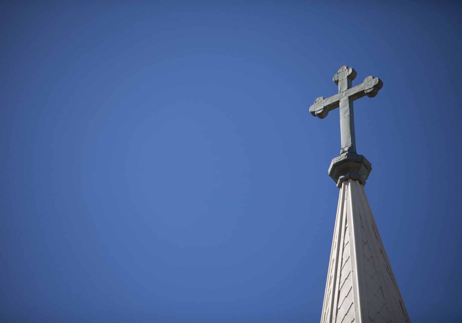 A cross on top of the steeple of a church.