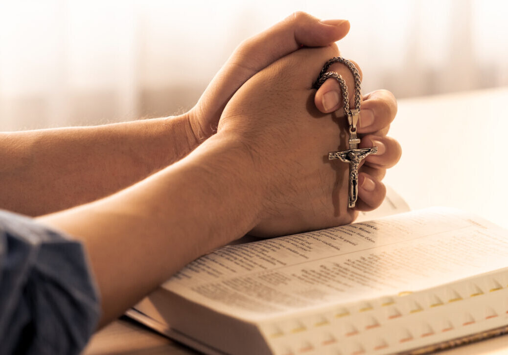 A person holding their hands together with keys in front of them.