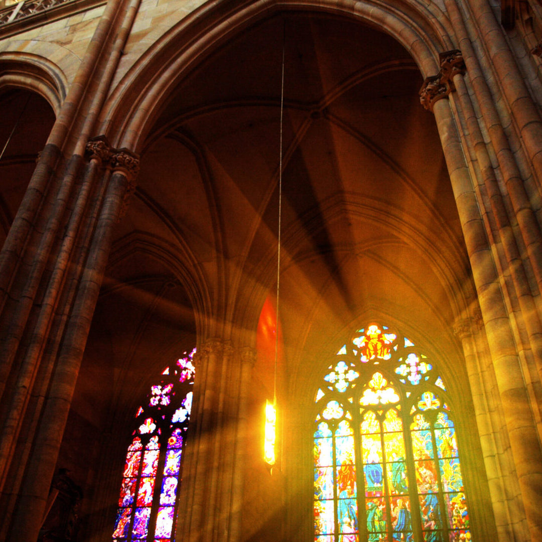 A cathedral with stained glass windows and sunlight coming through the window.