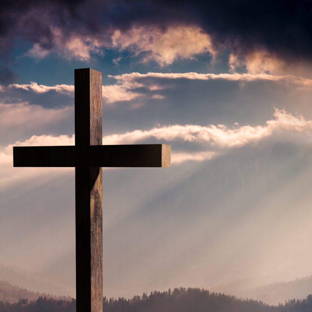 A cross is shown against the sky with clouds.