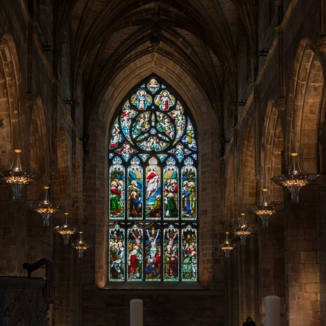 A stained glass window in the middle of an old church.